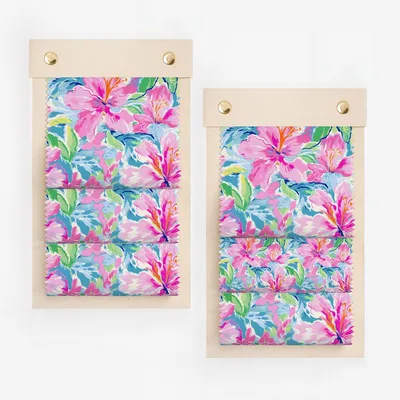 Two swatches of fabric with a bright floral pattern of pink, blue, and green flowers.