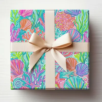 Gift wrapped in colorful coral, seashell, and starfish patterned paper with a tan ribbon.