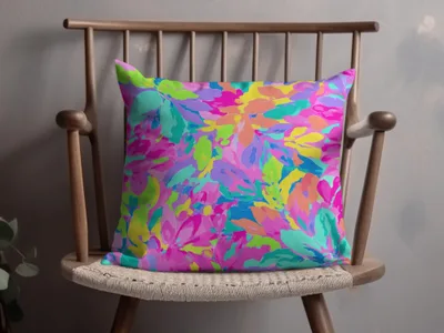 Colorful abstract floral pattern pillow on a wooden chair.