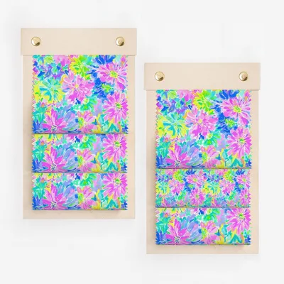 Two fabric swatch books with vibrant floral pattern in pink, blue, and green.