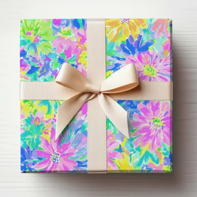 Gift box wrapped in colorful floral paper, tied with a beige ribbon.