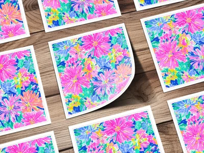 Several square cards with a bright floral pattern arranged on a wooden surface.