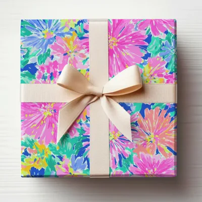 Gift box wrapped in colorful floral paper with a light beige ribbon.