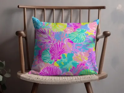 Colorful seashell pattern on a throw pillow on a wooden chair.