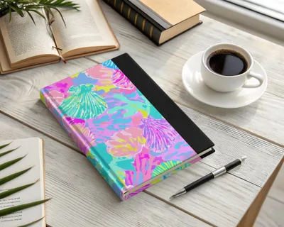 Journal with a colorful seashell pattern, open book, and coffee cup.