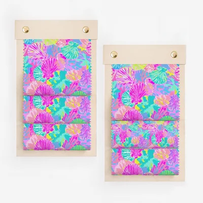 Two swatch books showcasing a coral and shell pattern in vibrant pink, blue, and yellow.