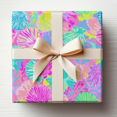 Gift box wrapped in colorful seashell pattern with a beige ribbon.