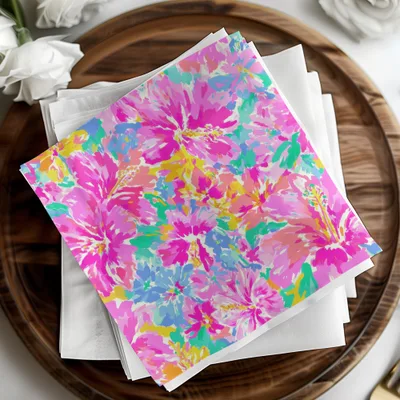 Colorful hibiscus floral print napkins stacked on white napkins.