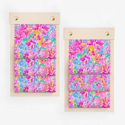 Two fabric swatches with a vibrant floral pattern on a light wooden backing.