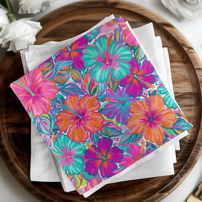 Colorful hibiscus floral pattern on folded paper napkins, arranged on a wooden tray.