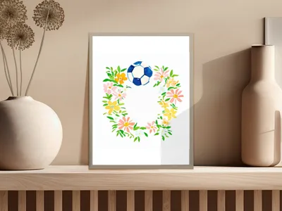 Watercolor soccer ball and floral wreath in a white frame on a shelf.