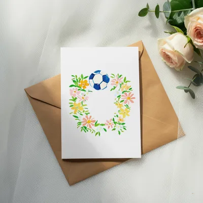 Card with floral wreath and soccer ball, on brown envelope.