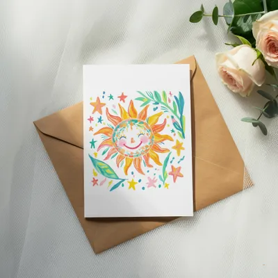 Hand-drawn sun with stars and leaves on a blank card over an envelope.