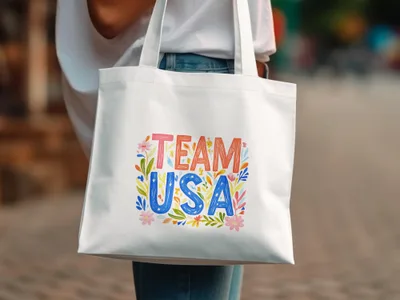 White tote bag with "TEAM USA" in colorful lettering and floral accents.