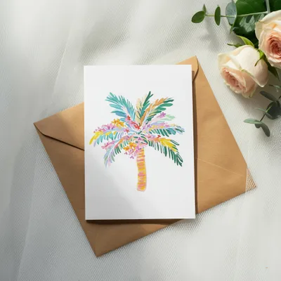 Watercolor palm tree card with colorful fronds on brown envelope.