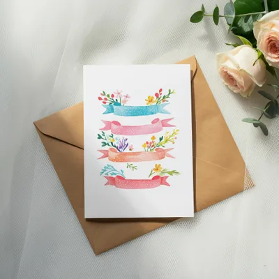 Card with watercolor banners and floral accents on brown envelope.