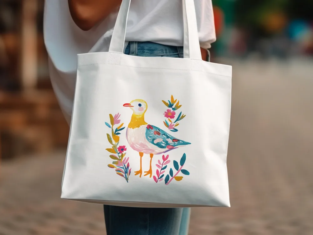 White tote bag with a colorful bird and floral illustration.