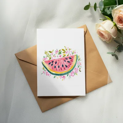 Card with watercolor watermelon slice surrounded by pink flowers, on brown envelope.