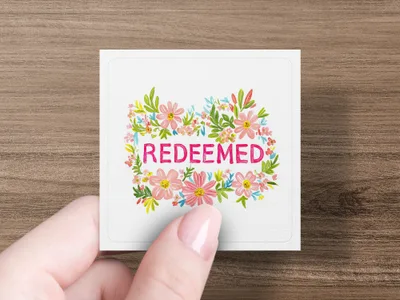 Square card with "Redeemed" text surrounded by pink and blue floral wreath.