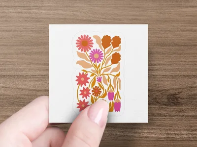 Hand holding sticker with folk art floral design in pinks and oranges.