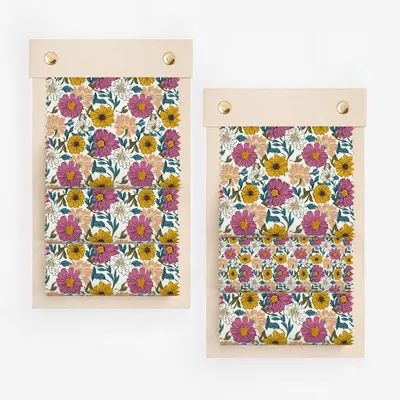 Two wooden notebooks display a floral pattern of pink, yellow, and purple flowers.
