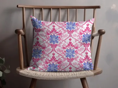 Decorative throw pillow with pink and blue floral damask pattern on a wooden chair.