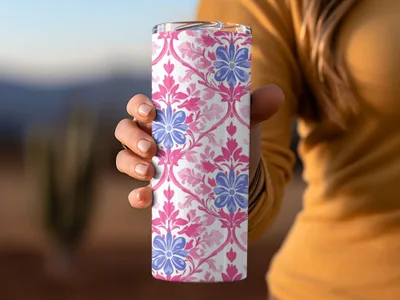 Pink and blue floral damask pattern on a white tumbler held by a hand.