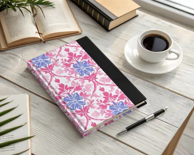 Notebook with pink and blue floral pattern next to coffee and pen.