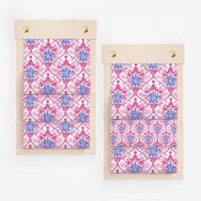 Two fabric swatches with a pink and blue floral pattern on a wooden board.