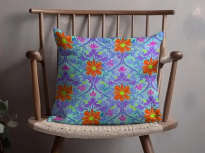 Patterned throw pillow with orange flowers and purple floral designs on a light blue background.