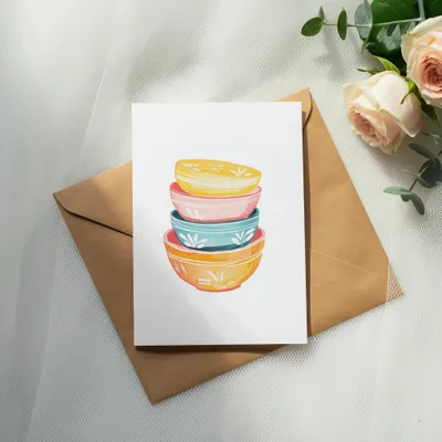 Watercolor painting of stacked colorful bowls on a brown envelope.