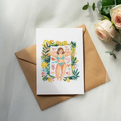 Card featuring a woman sunbathing on a towel surrounded by flowers.