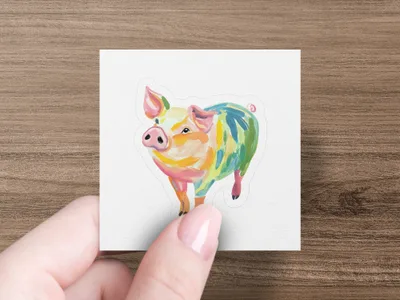 Colorful pig illustration on a white sticker held by a hand.