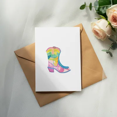 Watercolor cowboy boot illustration on a card, resting on a kraft envelope.
