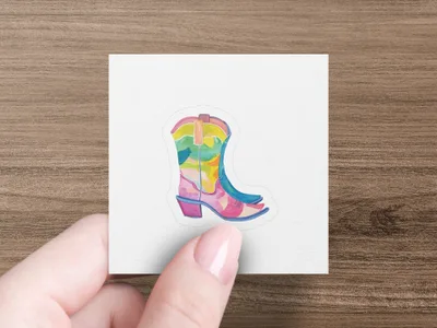 Colorful cowboy boot sticker on a white background held by fingers.