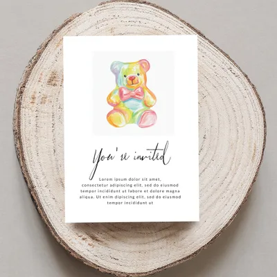 Invitation with a rainbow teddy bear and "You're invited" text.