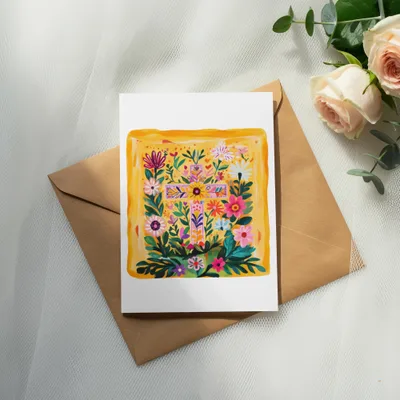 Floral cross design on a white card atop a brown envelope with roses.