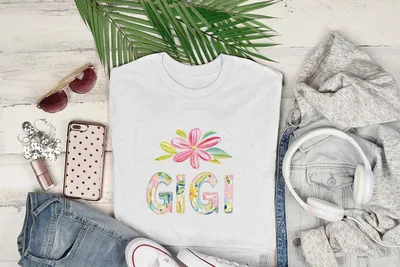 White t-shirt with "GIGI" in colorful floral letters, styled with jeans and headphones.