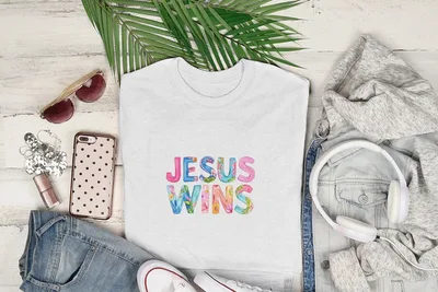 White t-shirt with "Jesus Wins" text in colorful watercolor floral letters.