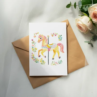 Watercolor carousel horse with floral garland on a brown envelope.