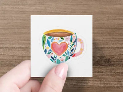 Mug with heart and floral design, held by a hand.