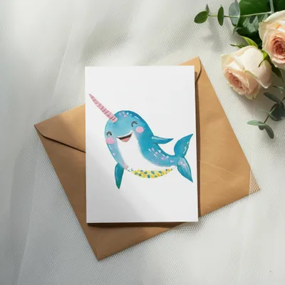 Cartoon narwhal with pink horn and blue spotted body on a card.