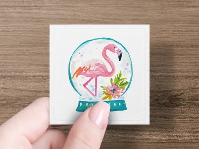 Flamingo inside a snow globe with flowers, held by a hand.