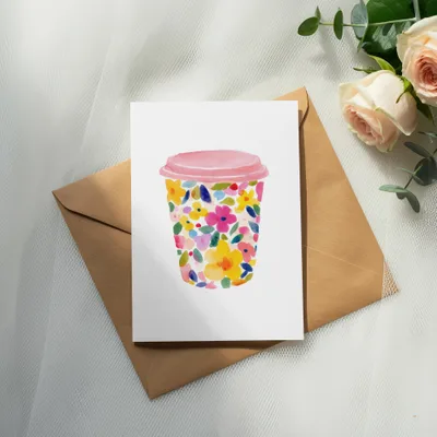 Floral watercolor coffee cup illustration on a white card, with a kraft envelope and roses.