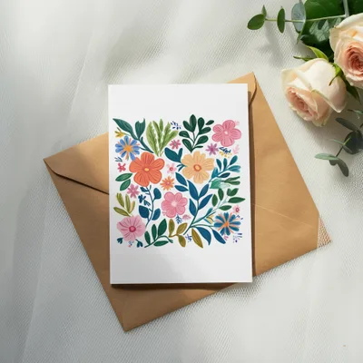 Card with colorful floral illustration on kraft paper envelope, with roses and eucalyptus.