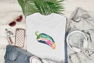 White t-shirt with colorful pepper illustration, surrounded by clothing and accessories.