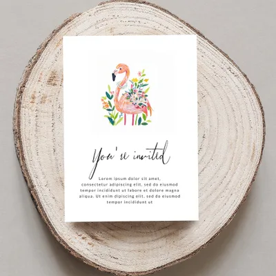 Flamingo and floral invitation on a wood slice.