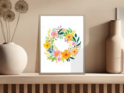 Floral wreath artwork in a light frame on a shelf.