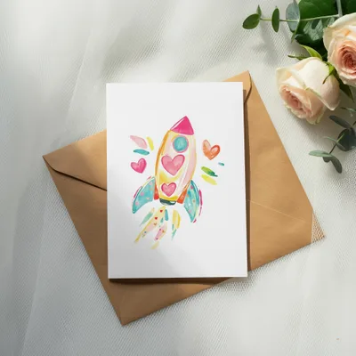 Watercolor illustration of a colorful rocket with hearts, on a kraft envelope.