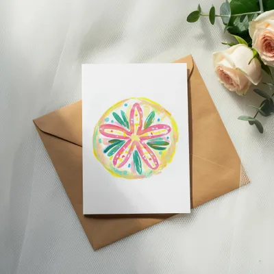 Watercolor floral design on card placed on brown envelope with roses.
